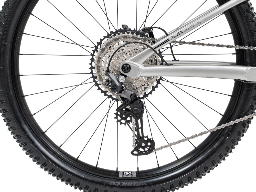 Rower górski MTB ROMET Dagger 2 29180130-B U18 29 cali Szaro-czarny białe tło zbliżenie na tylna przerzutkę napis Deore przerzutki marki SHIMANO 12 przełożeń duża wytrzymałość sprawne działanie zmiana biegów jest płynna i bezproblemowa tylny napęd SHIMANO Deore XT typu RD-M8100 wysoka trwałość stabilność precyzja precyzyjna praca mechanizmu