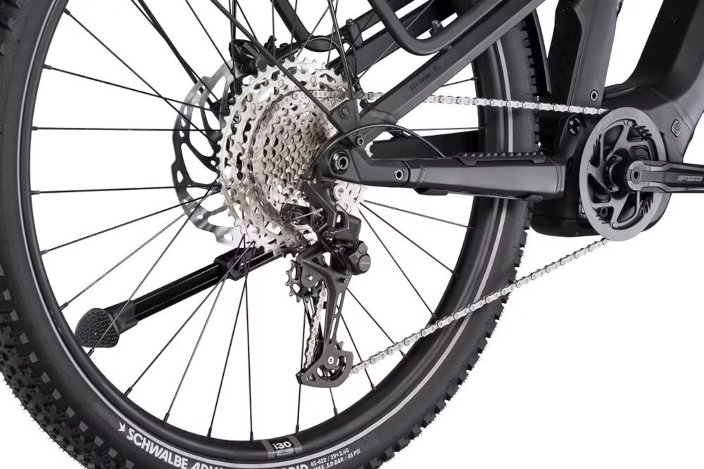 Zdjęcie przedstawia tylne koło roweru z widocznym mechanizmem przerzutki i łańcuchem. Na oponie widoczny jest napis \'SCHWALBE ADDIX\'.