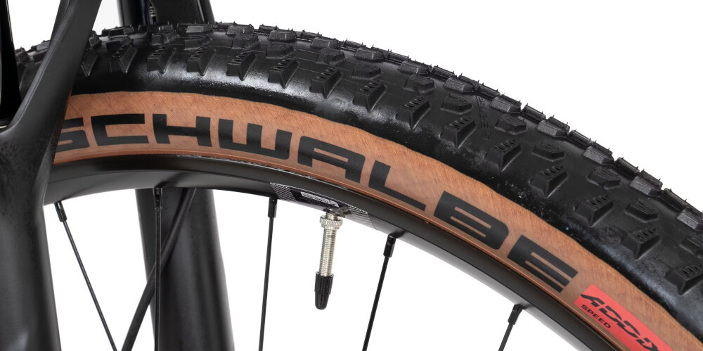 Zbliżenie na oponę rowerową z widocznym bieżnikiem i napisem \'SCHWALBE\'.