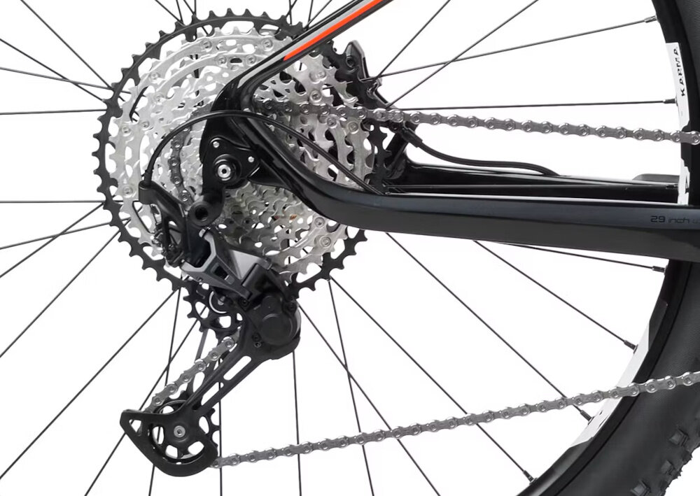 Zdjęcie przedstawia mechanizm przerzutki rowerowej z widocznymi zębatkami i łańcuchem. Elementy są w kolorze czarnym i srebrnym.