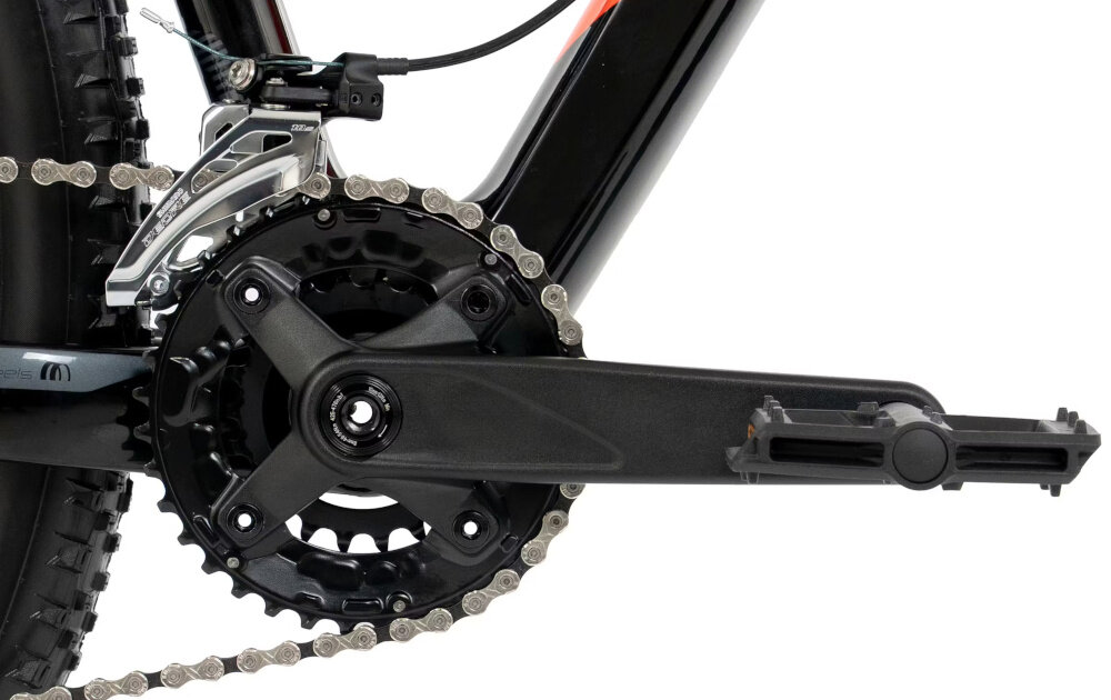 Zbliżenie na mechanizm korbowy roweru górskiego z czarną ramą i łańcuchem. Widoczny jest pedał oraz przednia przerzutka.
