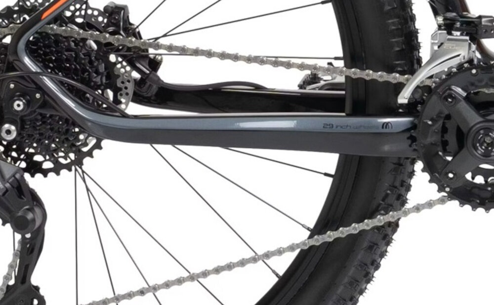 Zbliżenie na mechanizm napędowy roweru górskiego z widocznym łańcuchem, zębatkami i częścią ramy. Na ramie znajduje się napis \'29 inch\'.