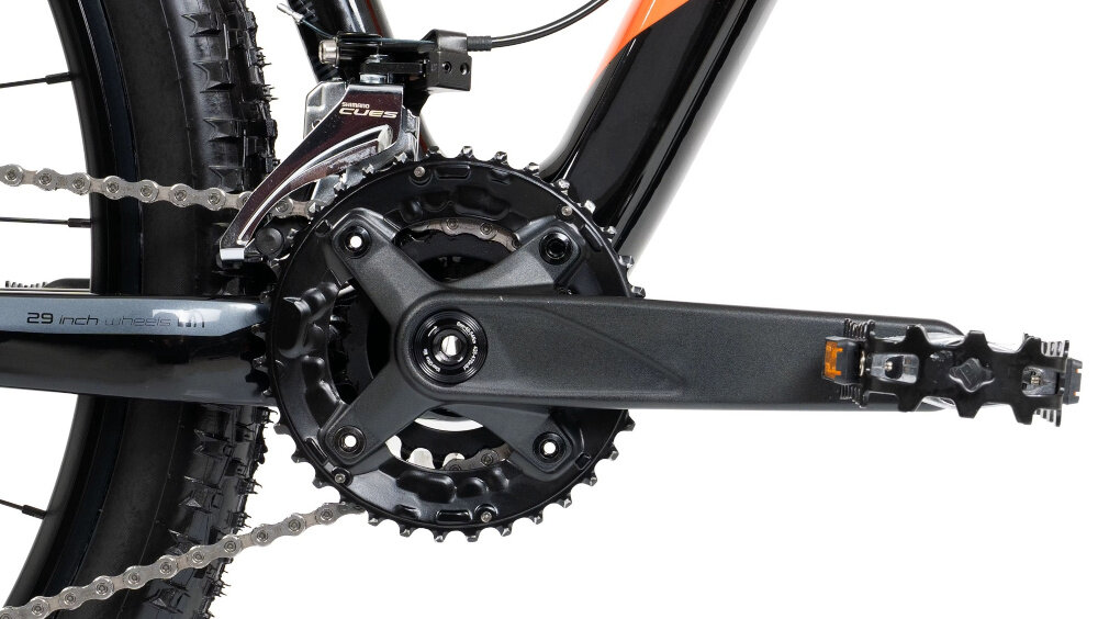 Zbliżenie na mechanizm korbowy roweru górskiego z widocznymi zębatkami i pedałem. Na ramie widoczny napis \'29 inch wheels\'.