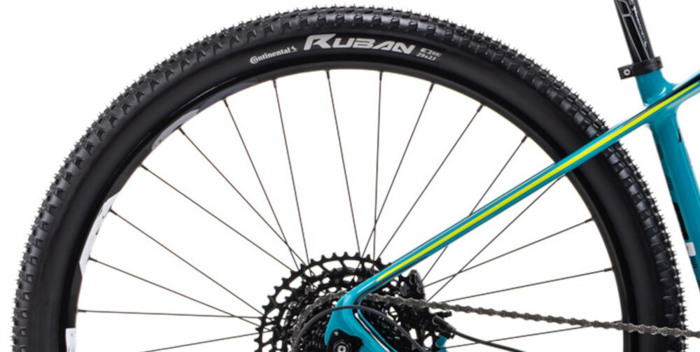 Rower górski MTB ROMET Monsun 2.0 29211345-B U21 29 cali Turkusowy zbliżenie na tylną oponę widok z boku opony marki CONTINENTAL RUBAN w rozmiarze 29 cali głęboki bieżnik skutecznie wspiera jazdę obręcze marki Mach 1 Karma piasty SHIMANO w standardzie HB-TC500 15 x 110 mm z przodu i FH-TC500 12 x 148 mm z tyłu sztywność kół regularne sprawdzanie ciśnienia powietrza wartość na bocznej części opony
