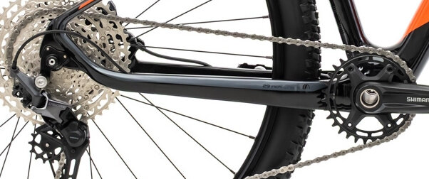Zbliżenie na mechanizm napędowy roweru górskiego z widoczną zębatką, łańcuchem i przerzutką. Na ramie znajduje się napis \'29 INCH\' oraz logo \'Shimano\' na korbie.