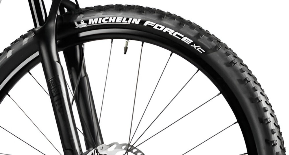 Zbliżenie na przednie koło roweru z widoczną oponą marki MICHELIN FORCE XC. W tle widać część widelca i tarczę hamulcową.