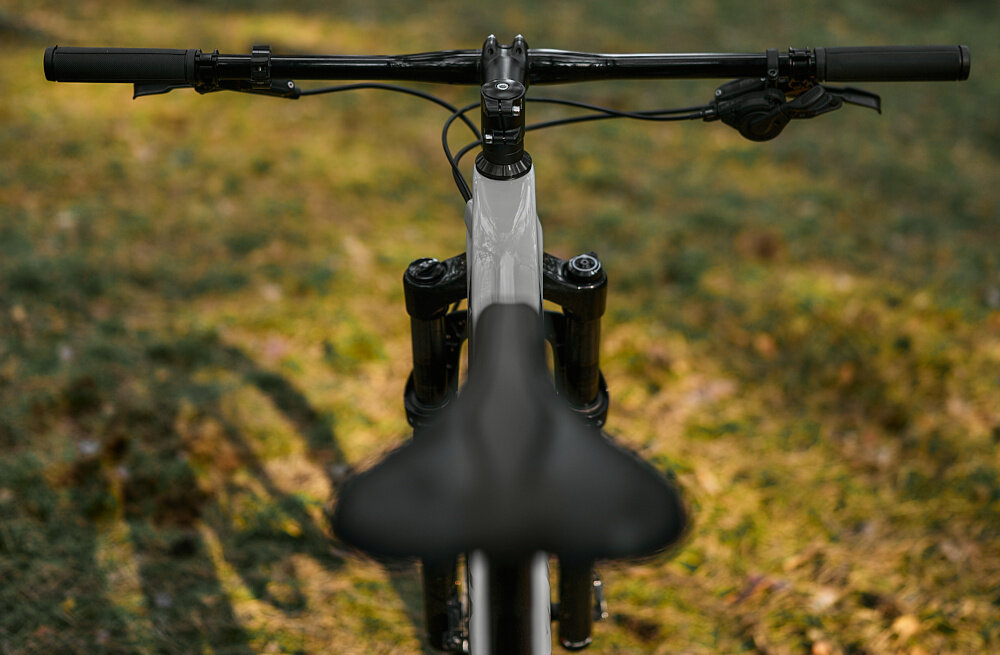 Rower górski MTB ROMET Monsun 3.1 29152260-B U15 29 cali Szary rozmazane tło droga leśna zbliżenie na kierownicę widok od przodu kierownica marki ROMET o szerokości 760 mm precyzyjne manewrowanie i omijanie przeszkód aluminiowy wspornik ROMET typu JD-SD-2202B o długości 80 mm