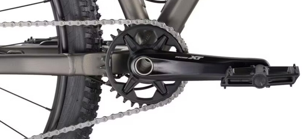 Zbliżenie na mechanizm korbowy roweru z widocznym napisem \'Shimano XT\'.