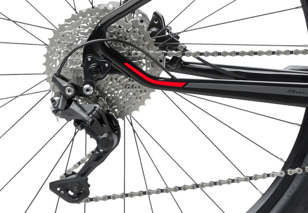 Zdjęcie przedstawia tylną część roweru z widocznym mechanizmem przerzutki i kasetą zębatek. Rama roweru jest czarno-czerwona z napisem \'29 inch\'.