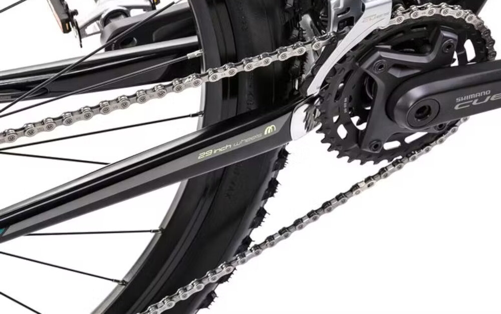 Zbliżenie na mechanizm napędowy roweru z widocznym łańcuchem i zębatkami. Na ramie znajduje się napis \'29 inch wheels\' oraz logo \'Shimano\'.