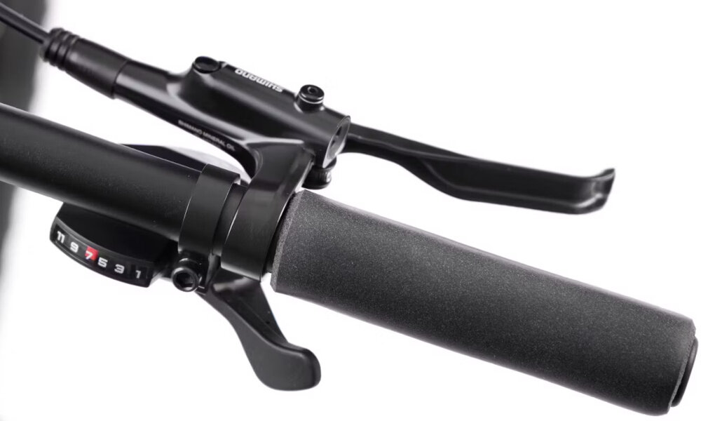 Rower górski MTB ROMET Mustang Evo 2 CS 29190157-B U19 29 cali Grafitowo-granatowy zbliżenie na manetkę kierownicy białe tło widok od przodu kierownica marki ROMET o szerokości 760 mm i średnicy mocowania 31,8 mm ułatwia precyzyjne manewrowanie i omijanie przeszkód aluminiowy wspornik ROMET o długości 90 mm i średnicy 31,8 mm komfort i kontrola