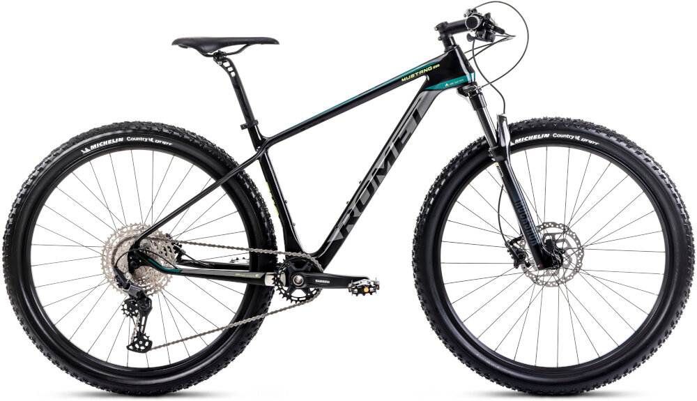 Rower górski MTB ROMET Mustang EVO 3 29170148-A U17 29 cali Czarno-zielony rower na białym tle widoczny z boku rozmazane tło jazda na rowerze pasja hobby