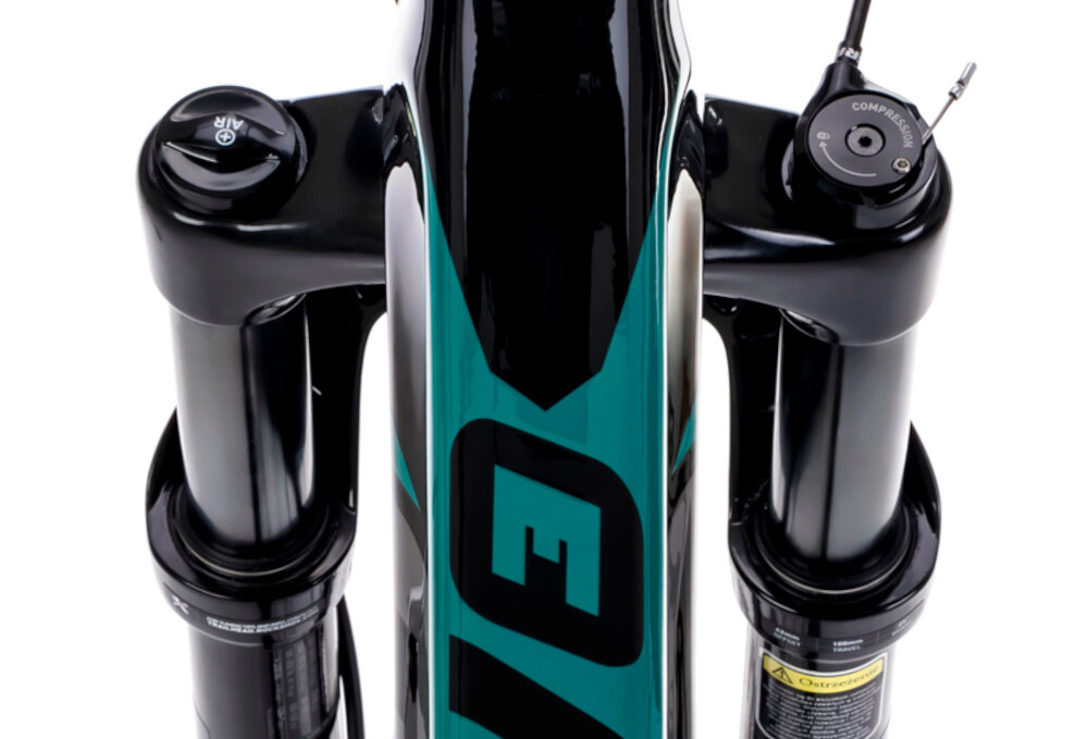 Rower górski MTB ROMET Mustang EVO 3 29170148-A U17 29 cali Czarno-zielony zbliżenie na amortyzator białe tło widok od przodu z góry konstrukcja hardtail z przednim amortyzatorem marki ROCK SHOX typu Recon Silver RL Boost 15 x 110 mm Tapered ze skokiem 100 mm pomaga ograniczyć drgania przenoszone z podłoża ułatwia utrzymanie kontroli nad rowerem sprzyja również bardziej efektywnemu pedałowaniu