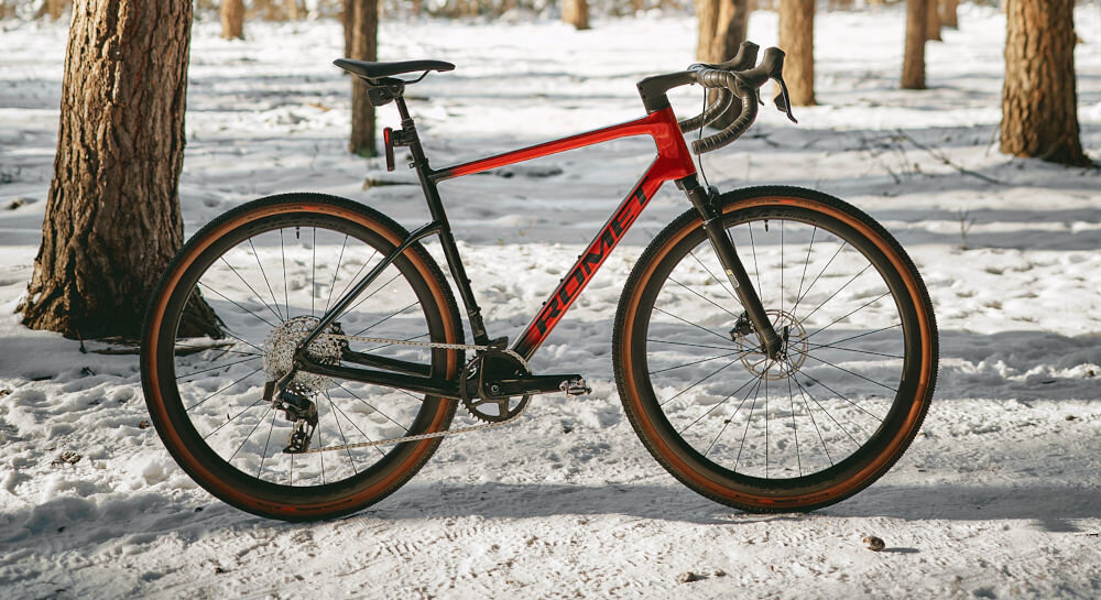 Rower gravel ROMET NYK 3.0 SRAM 28560364-A U22 28 cali męski Czerwono-czarny zimowa sceneria rower widoczny bokiem ustawiony na śniegu w lesie pasja hobby lekkość wszechstronność