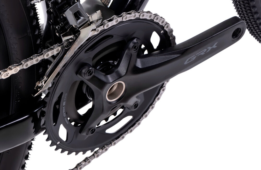 Rower gravel ROMET NYK 2.0 28460099-A U17 28 cali Fioletowy zbliżenie na korbę i kasetę białe tło precyzyjny napęd oparty na komponentach SHIMANO 12-biegowa kaseta SHIMANO GRX CS-HG710 o szerokim zakresie 11-36T korba SHIMANO typu GRX FC-RX610-2 46 - 30T 170 mm