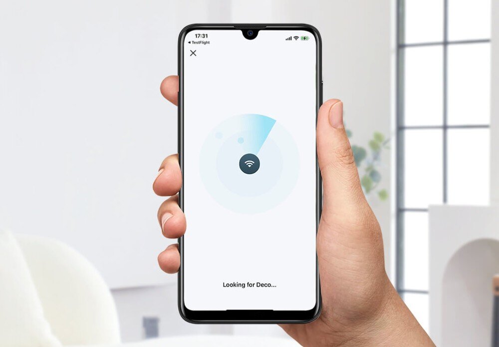 Router TP-LINK Deco x50-5G Dłoń trzymająca smartfon z otwartą aplikacją do zarządzania siecią, ekran pokazuje proces wyszukiwania urządzenia Deco, aplikacja, funkcje, narzędzia