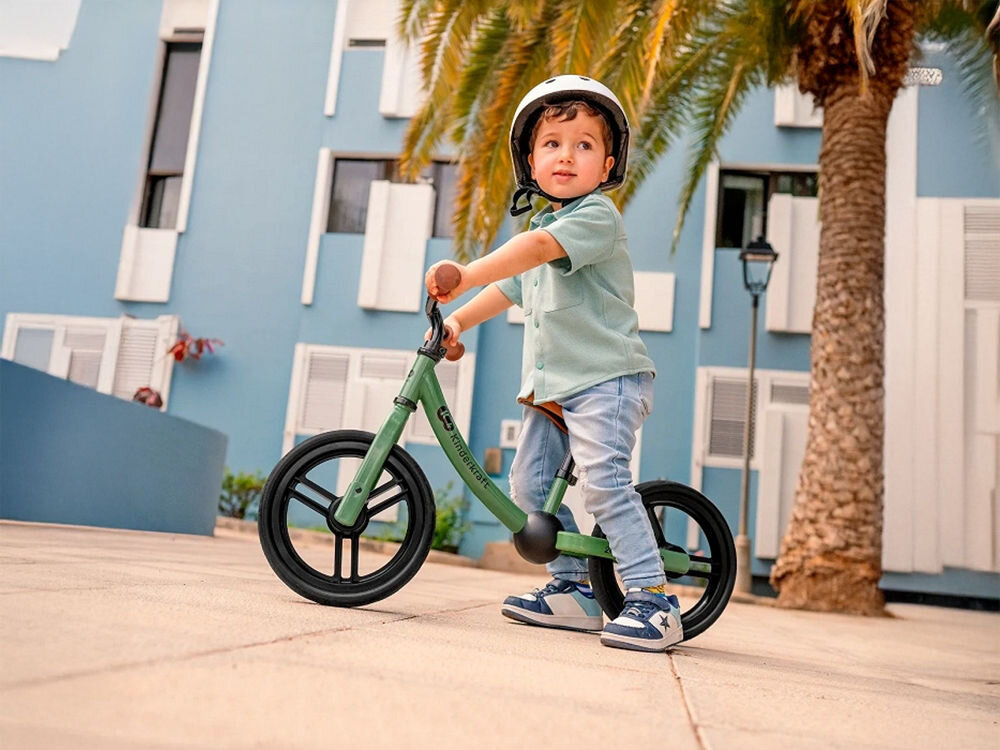 Rowerek biegowy 2WAY NEXT 2022 BLUE dziecko siedzi na zielonym rowerku czarne koła gumowe uchwyty na kierownicy białe tło dla dzieci od 2 roku życia stabilna konstrukcja bezpieczeństwo lekka budowa łatwe prowadzenie rozwijanie samodzielności Kompaktowe rozmiary dostosowany do potrzeb najmłodszych maksymalne obciążenie do 35 kg dla maluchów od pierwszych lat życia