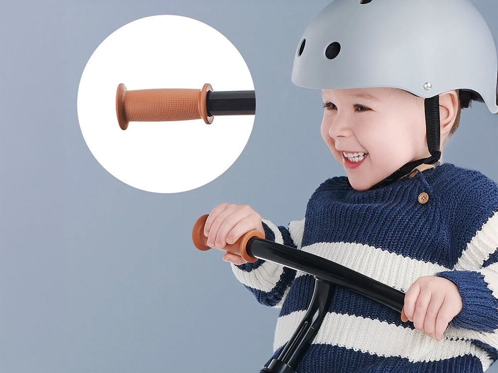 Rowerek biegowy 2WAY NEXT 2022 BLUE ciemne tło dziecko trzyma gumowe uchwyty na kierownicy  Rączki w rowerku komfort bezpieczeństwo miękka gumowa powłoka wolna od szkodliwych substancji Antypoślizgowa tekstura pewnie trzymać kierownicę Ergonomiczne uchwyty wspierają naukę prawidłowej postawy