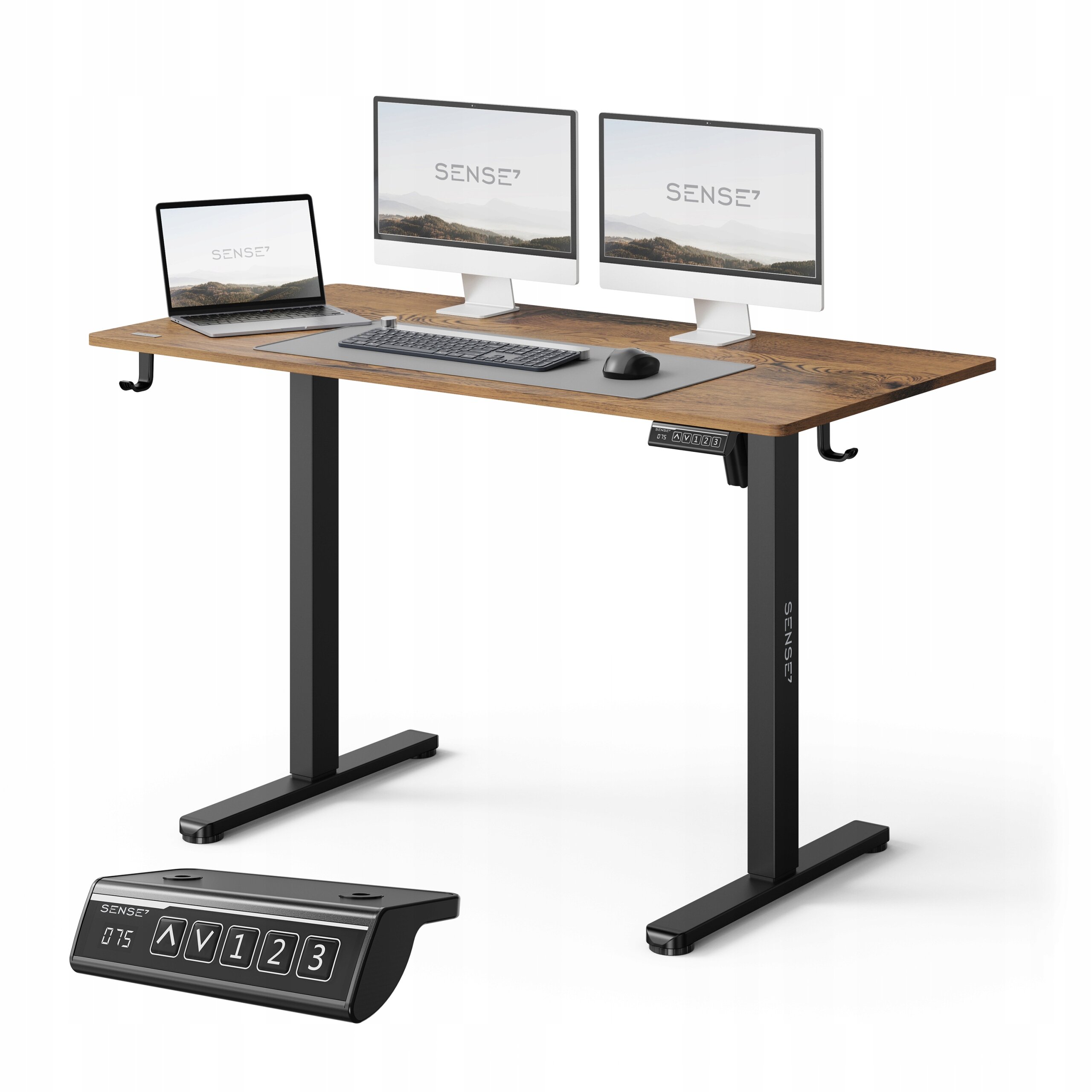 Na obrazie widoczne jest biurko z ciemnobrązowym blatem, na którym znajdują się dwa monitory, laptop, klawiatura i myszka. Obok biurka pokazany jest panel sterowania z przyciskami i wyświetlaczem, na którym widnieje napis \'SENSE7\'.
