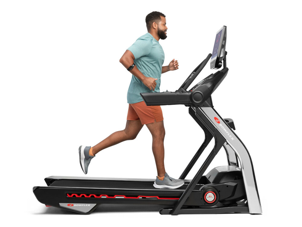 Bieżnia elektryczna BOWFLEX T56 2941W 20km-h osoba biegnie na bieżni na białym tle trening w domowym zaciszu funkcje umożliwiające dostosowanie prędkości i nachylenia zróżnicowane treningi wszechstronność