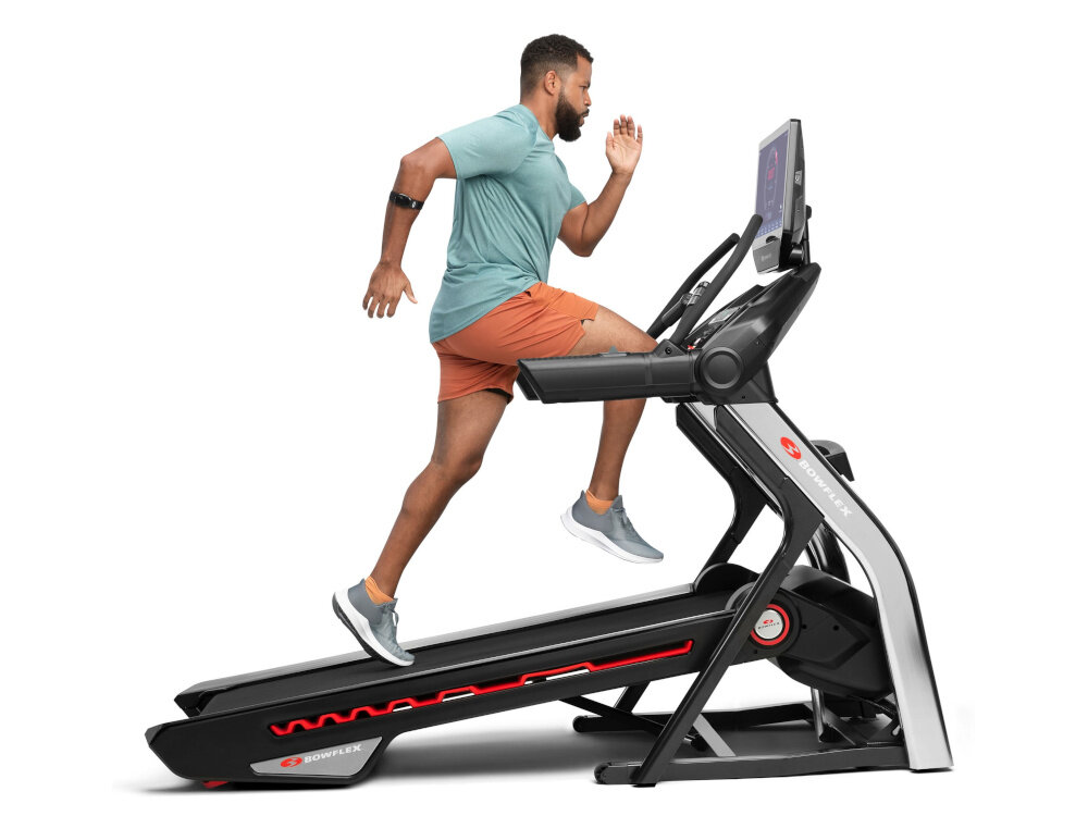 Bieżnia elektryczna BOWFLEX T56 2941W 20km-h osoba biegnie na bieżni na białym tle regulacja kąta nachylenia pasa biegowego w zakresie od -5% do 20% symulacja biegu w różnych warunkach skuteczna praca nad dolną częścią ciała poprawa ogólnej wydolności organizmu możliwość biegu w dół