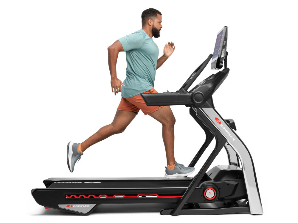 Bieżnia elektryczna BOWFLEX T56 2941W 20km-h osoba biegnie na bieżni na białym tle komfort użytkowania bezpieczeństwo antypoślizgowa powierzchnia pasa biegowego stabilny krok system amortyzacji redukuje wstrząsy
