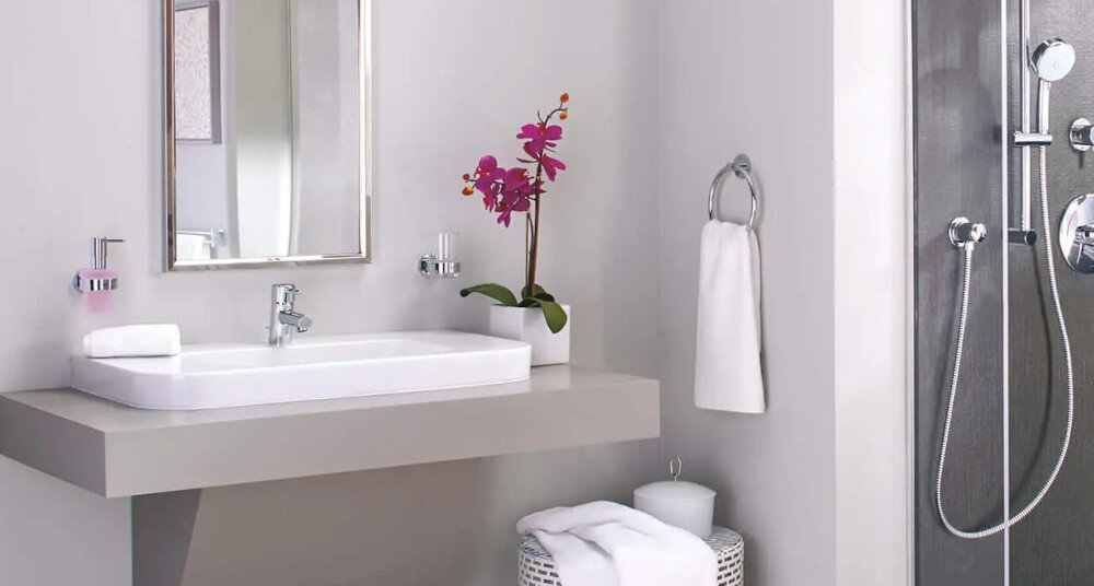 DOZOWNIK GROHE ESSENTIALS 40394001 CHROM Łazienka z umywalką na blacie, lustrem, kwiatem w doniczce oraz kabiną prysznicową po prawej stronie dozownik montaż ścienny dedykowane uchwyty różne style kolory dopasowanie GROHE Essentials Bau Cosmopolitan