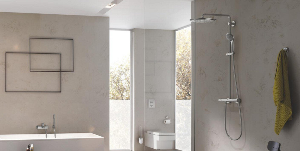 HACZYK NA PŁASZCZ KĄPIELOWY GROHE ESSENTIALS 40364DC1 Stal nierdzewna Jasna łazienka z wiszącą szafką i umywalką, nad którą znajduje się okrągłe lustro, a obok wiszą dwa ręczniki. Jasne płytki i drewniane elementy tworzą minimalistyczny, elegancki wystrój