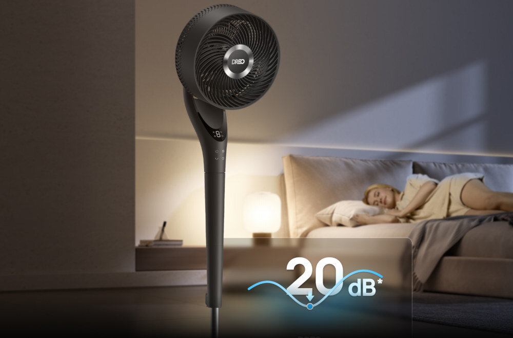 Czarny wentylator stojący z widocznym logo \'DREO\' na tle sypialni, w której osoba śpi na łóżku. Na obrazie widoczny jest napis \'20 dB\'.