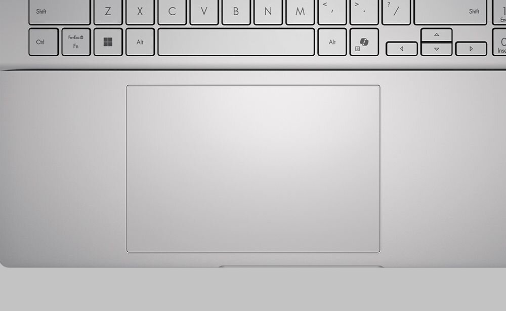 Obraz przedstawia klawiaturę laptopa z widocznym touchpadem poniżej. Klawisze są w kolorze srebrnym z czarnymi oznaczeniami liter i symboli.
