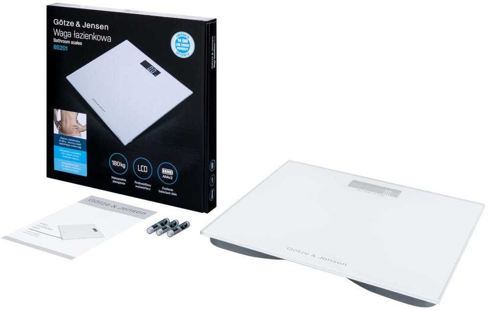 Na obrazie znajduje się biała waga łazienkowa Götze & Jensen z wyświetlaczem LCD oraz opakowanie z grafiką produktu i tekstem \'Götze & Jensen Waga łazienkowa BS201\'. Obok wagi leżą trzy baterie i instrukcja obsługi.