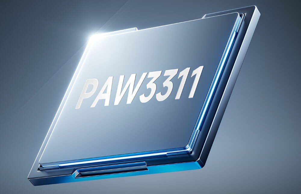 Mysz AJAZZ AJ199 Kwadratowy procesor komputerowy z błyszczącym napisem 'PAW3311' pokazany pod kątem na jednolitym, jasnym tle z delikatnymi refleksami światła, sensor, rozdzielczość, parametry