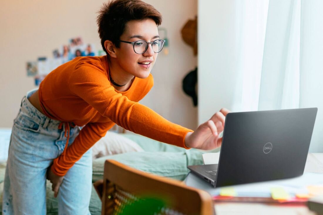 Osoba korzysta z laptopa marki DELL, który stoi na biurku w jasnym pomieszczeniu. Na obudowie laptopa widoczne jest logo DELL.