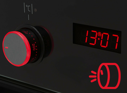Panel sterowania z pokrętłem i wyświetlaczem elektronicznym pokazującym godzinę 13:07. Obok znajduje się symbol czerwonego pokrętła z ikoną sygnalizującą dźwięk.