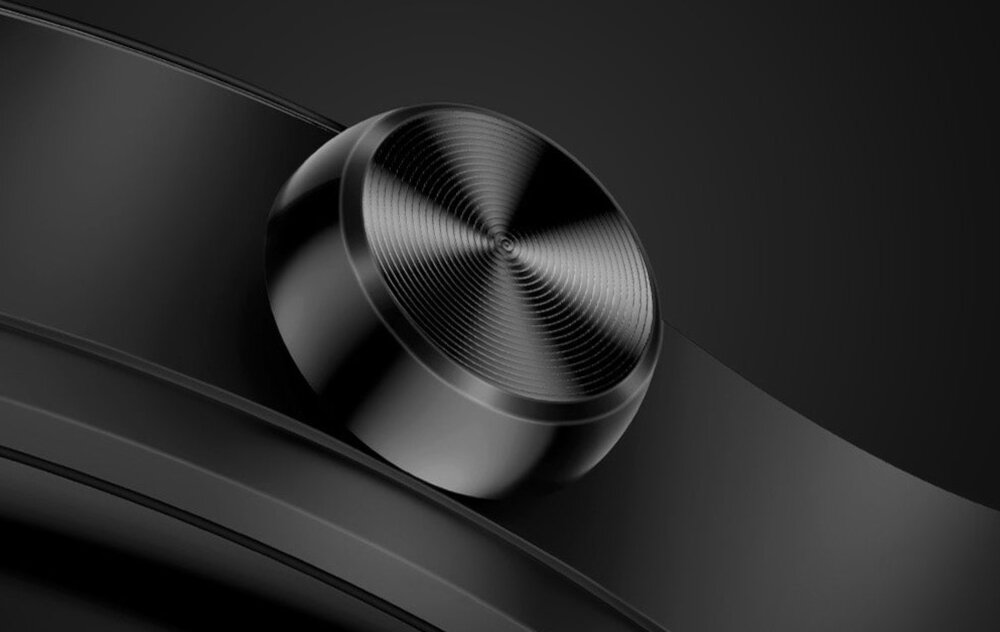 Zbliżenie na czarny przycisk obrotowy na urządzeniu elektronicznym z metalicznym wykończeniem. Tło jest ciemne, co podkreśla detale przycisku.