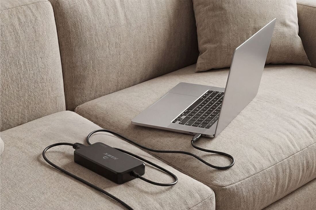 Laptop ładuje się przez zasilacz HAWK USB‑C GaN podłączony na sofie, wspierając komfortową pracę zdalną w domu 