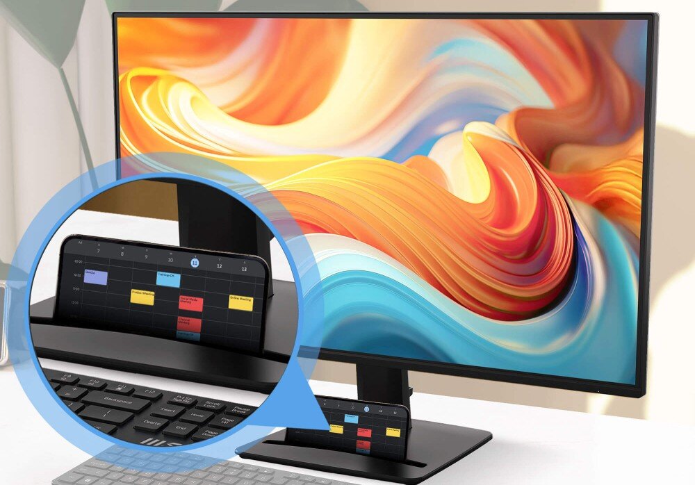 Monitor MSI Pro MP272 E14C Zbliżenie na podstawę monitora z poziomym wycięciem, w którym umieszczono smartfon wyświetlający kalendarz spotkań, podstawka, klips do kabli, regulacja pochylenia