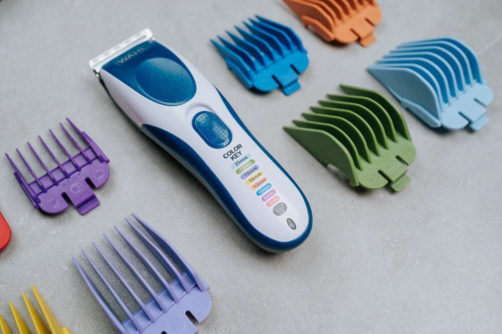Strzyżarka WAHL Color Pro Cordless 9649-016 1.5-25 mm maszynka w otoczeniu kolorowych nasadek na szarym tle, odpowiednia długość cięcia