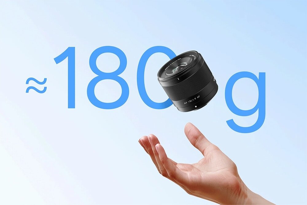 Na tle jasnoniebieskiego nieba widoczny jest obiektyw fotograficzny unoszący się nad otwartą dłonią. Obok obiektywu znajduje się tekst: \'≈ 180 g\'.