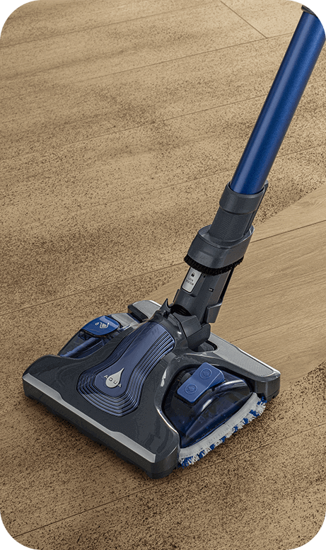 Odkurzacz z niebieską rurą i czarną głowicą czyszczącą, widoczny na drewnianej podłodze. Na głowicy znajduje się symbol kropli wody.