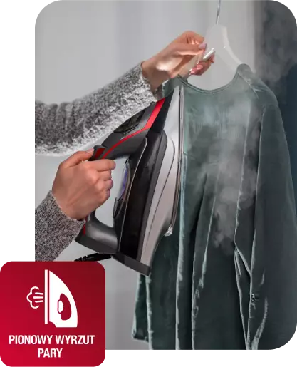Osoba prasuje wiszącą koszulę za pomocą żelazka parowego, z którego wydobywa się para. W lewym dolnym rogu znajduje się ikona z napisem \'PIONOWY WYRZUT PARY\'.