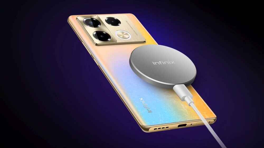 Smartfon z gradientową obudową w kolorach złotym i niebieskim, z trzema dużymi aparatami i jednym mniejszym. Na obudowie widoczne jest logo \'Infinix\' oraz podłączona okrągła ładowarka bezprzewodowa z napisem \'Infinix\'.