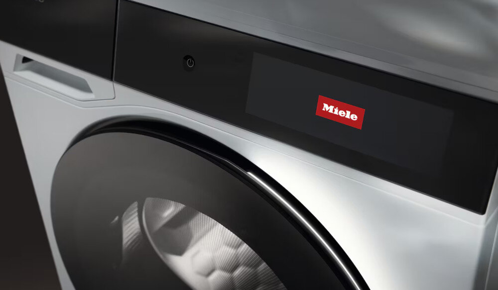 Widoczna jest część suszarki z okrągłym bębnem i panelem z logo Miele.