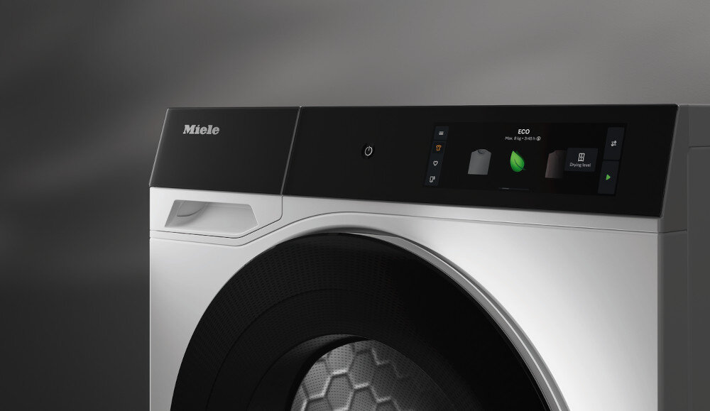 Widoczny jest fragment suszarki z panelem sterowania, na którym wyświetla się tekst: ECO. Logo Miele znajduje się na obudowie.