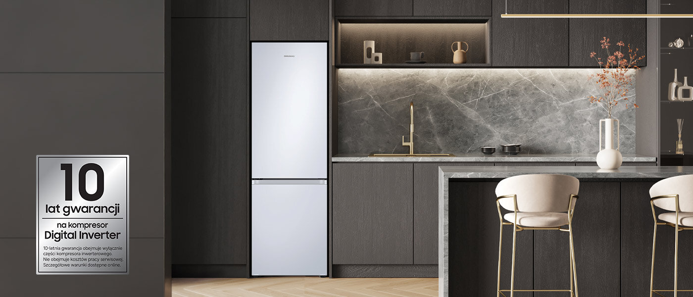 Lodówki Samsung posiadają 10-letnią gwarancję na kompresor Digital Inverter W nowoczesnej kuchni znajduje się biała lodówka w zabudowie, obok której widoczny jest marmurowy blat z krzesłami. Na ścianie po lewej stronie widnieje napis: \'10 lat gwarancji na kompresor Digital Inverter\'.