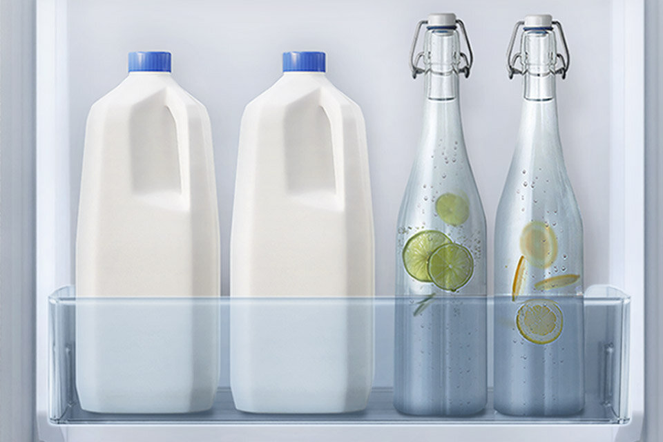 3 pojemniki na drzwiach Wnętrze lodówki z dwoma plastikowymi butelkami z niebieskimi zakrętkami oraz dwiema szklanymi butelkami z metalowymi zamknięciami. W szklanych butelkach znajdują się plasterki cytryny i limonki.