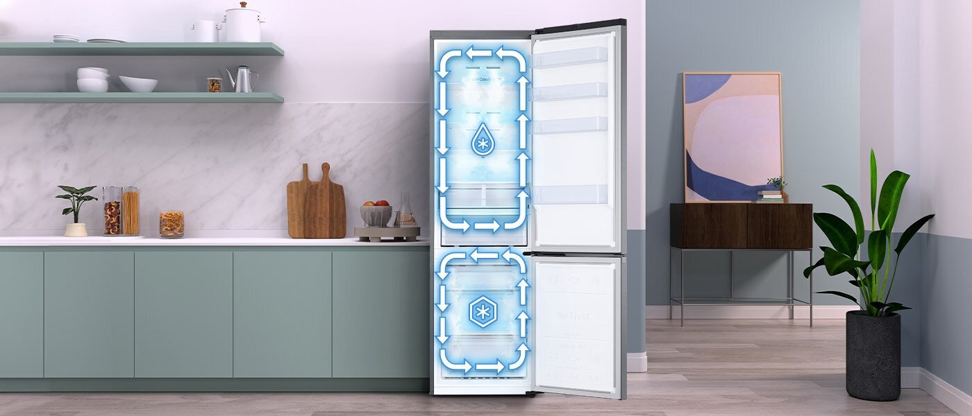 W kuchni znajduje się otwarta lodówka z widocznym systemem chłodzenia oznaczonym niebieskimi strzałkami i symbolami kropli oraz płatka śniegu. Obok lodówki jest szafka z blatem, na którym stoją deski do krojenia i pojemniki.