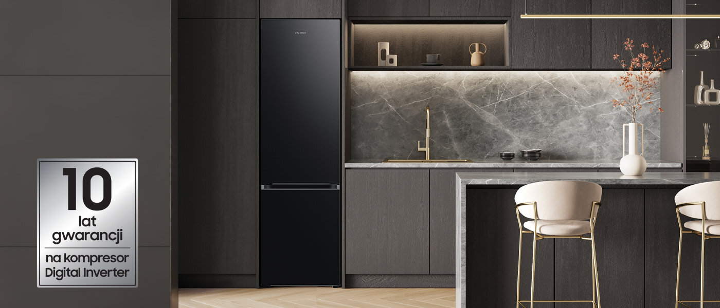 Kuchnia z ciemnymi szafkami i lodówką w kolorze grafitowej stali. Na obrazie widoczny jest napis: \'10 lat gwarancji na kompresor Digital Inverter\'.