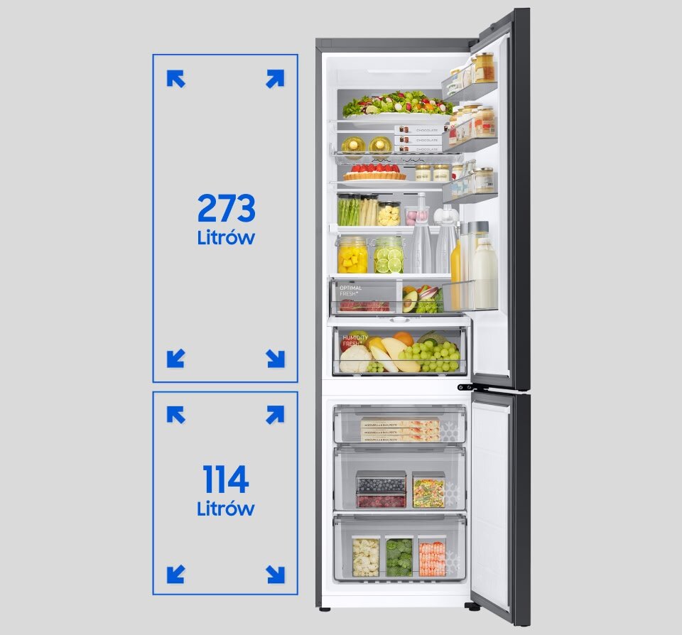 Otwarta lodówka z widocznymi półkami wypełnionymi różnymi produktami spożywczymi. Obok lodówki znajdują się oznaczenia pojemności: 273 litrów dla części chłodzącej i 114 litrów dla zamrażarki.