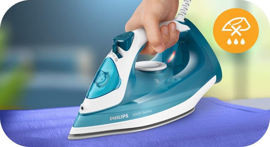 Osoba trzyma żelazko w kolorze niebiesko-białym z napisem \'PHILIPS 3000 Series\', prasując niebieski materiał. W prawym górnym rogu znajduje się pomarańczowa ikona z symbolem kropli wody i przekreślonym kranem.